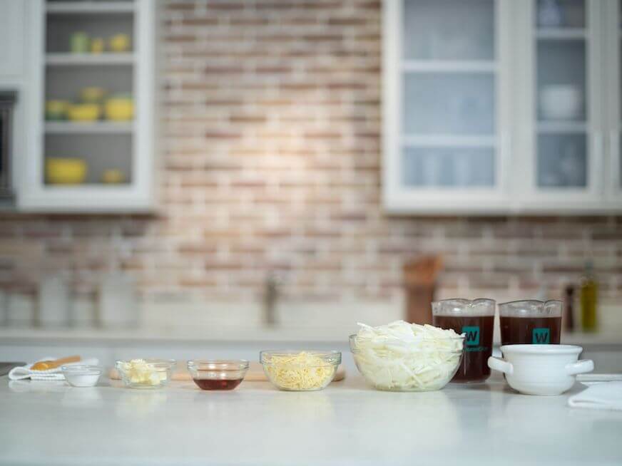 Mise en place untuk sup bawang Perancis, dengan kaldu coklat tua, semangkuk irisan bawang bombay, keju, saus worcestershire, mentega, dan garam.