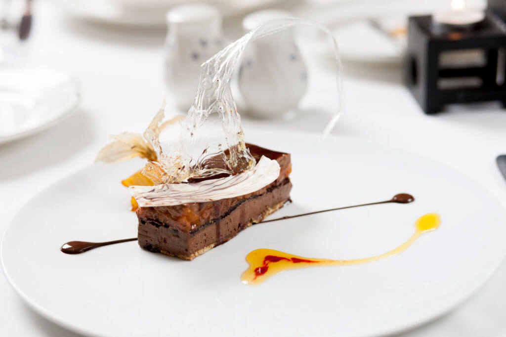 Chocolate dessert on white plate with clear transparent decoration